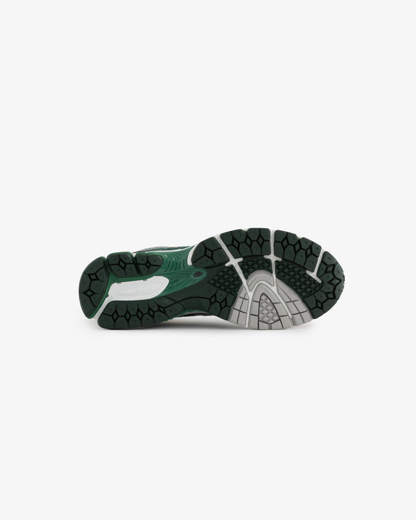 The image shows the outsole of a sneaker, featuring a textured, black rubber surface with a green accent. The design includes a combination of grooves and patterns for traction and support.