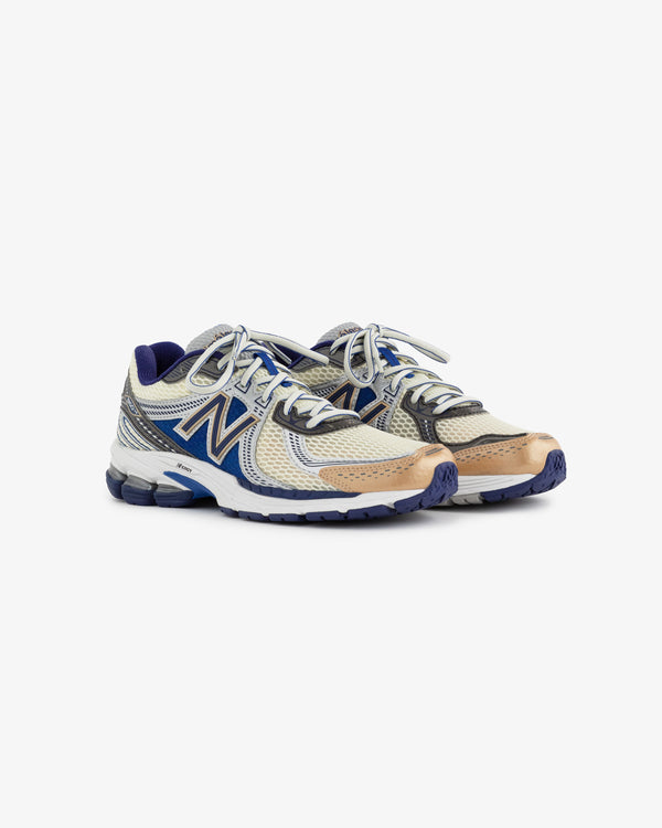 A pair of New Balance 860v2 running shoes featuring a blend of metallic gold, silver, and blue colors. The shoes have a sleek design with a mesh upper and cushioned sole, ideal for both style and comfort.