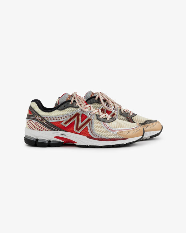 A pair of New Balance 860v2 running shoes featuring a beige and red color scheme. The shoes have a mesh upper, padded collar, and a cushioned sole, showcasing a sporty design ideal for running or casual wear.