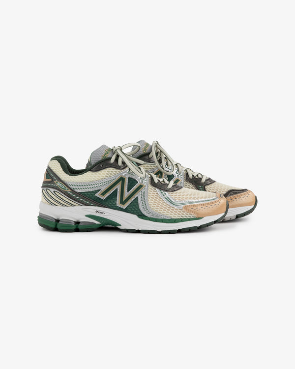 A pair of New Balance 860v2 sneakers featuring a mesh upper in shades of beige, green, and black. The shoes have a cushioned sole and prominent branding, showcasing a blend of style and comfort.