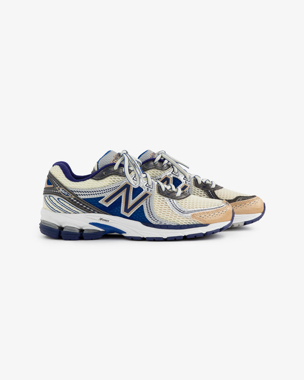 A pair of New Balance 860v2 running shoes featuring a beige mesh upper with navy accents. The shoes have a cushioned sole and are designed for comfort and performance, showcasing a sleek and modern silhouette.