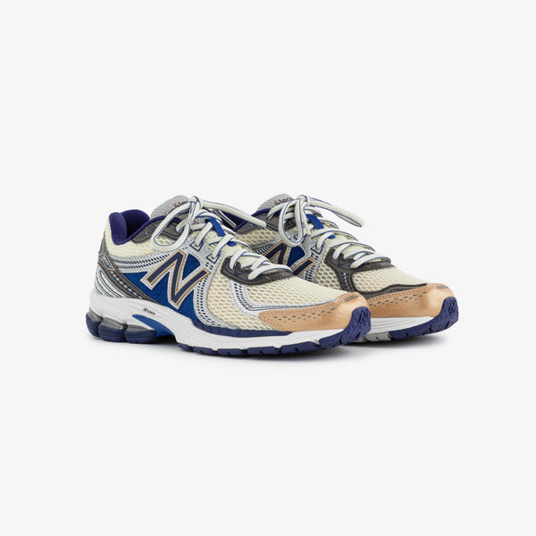 A pair of New Balance 860v2 running shoes featuring a beige and blue color scheme, with a mesh upper for breathability and a cushioned sole for comfort. The shoes are displayed on a plain white background.